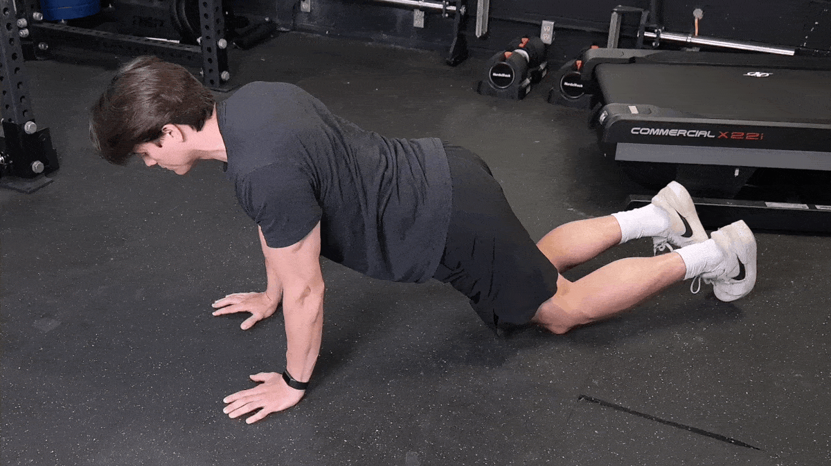 BarBend's Jake Herod performing the assisted push-up exercise.