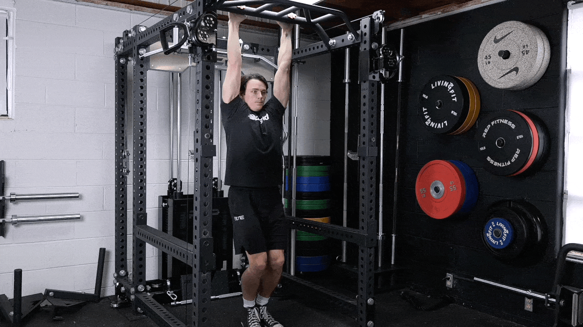 BarBend's Jake Herod hanging from a pull-up bar and raising his legs.