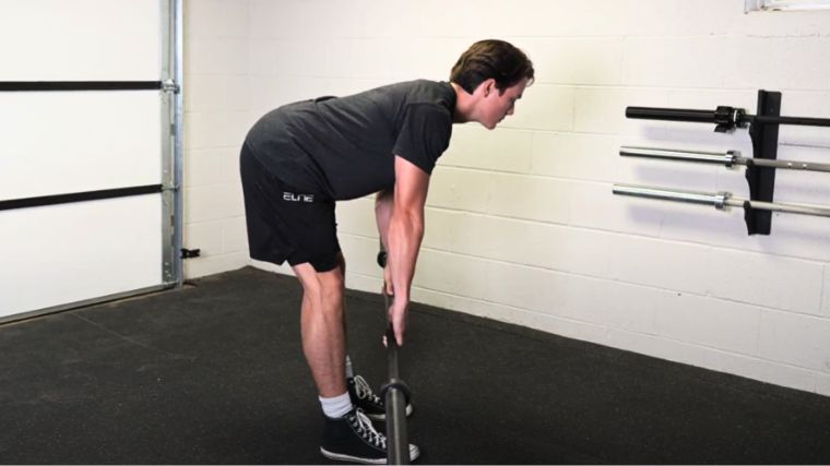 BarBend's Jake Herod performing the stiff-leg deadlift with an empty barbell.